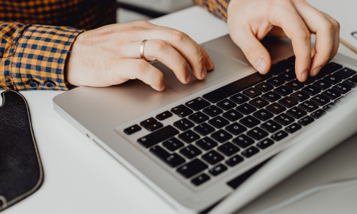 A close-up of hands typing on a laptop.